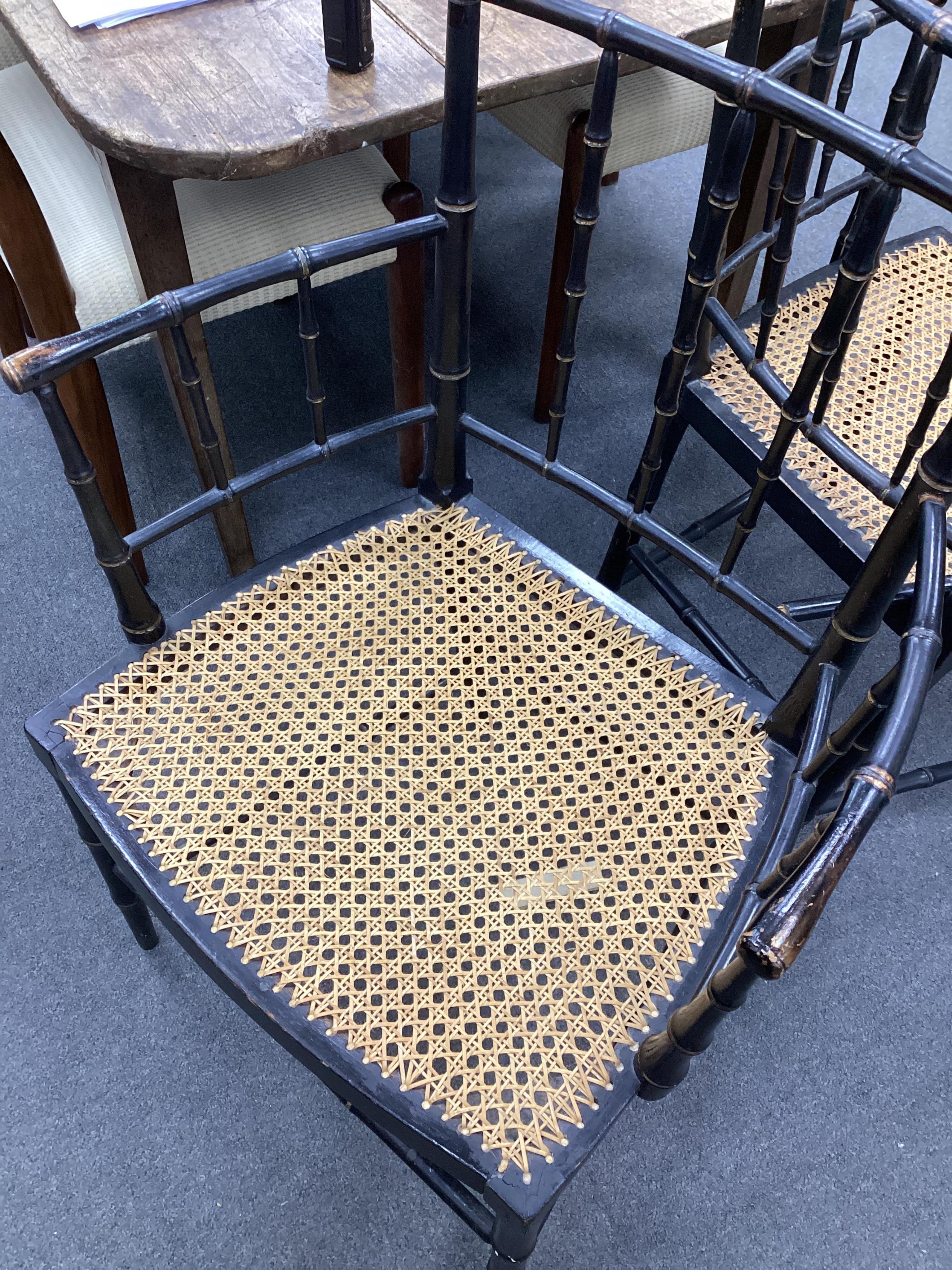 A set of four Regency ebonised simulated bamboo cane seat elbow chairs, width 56cm, depth 43cm, height 86cm. Condition - fair (one stretcher detached but present)